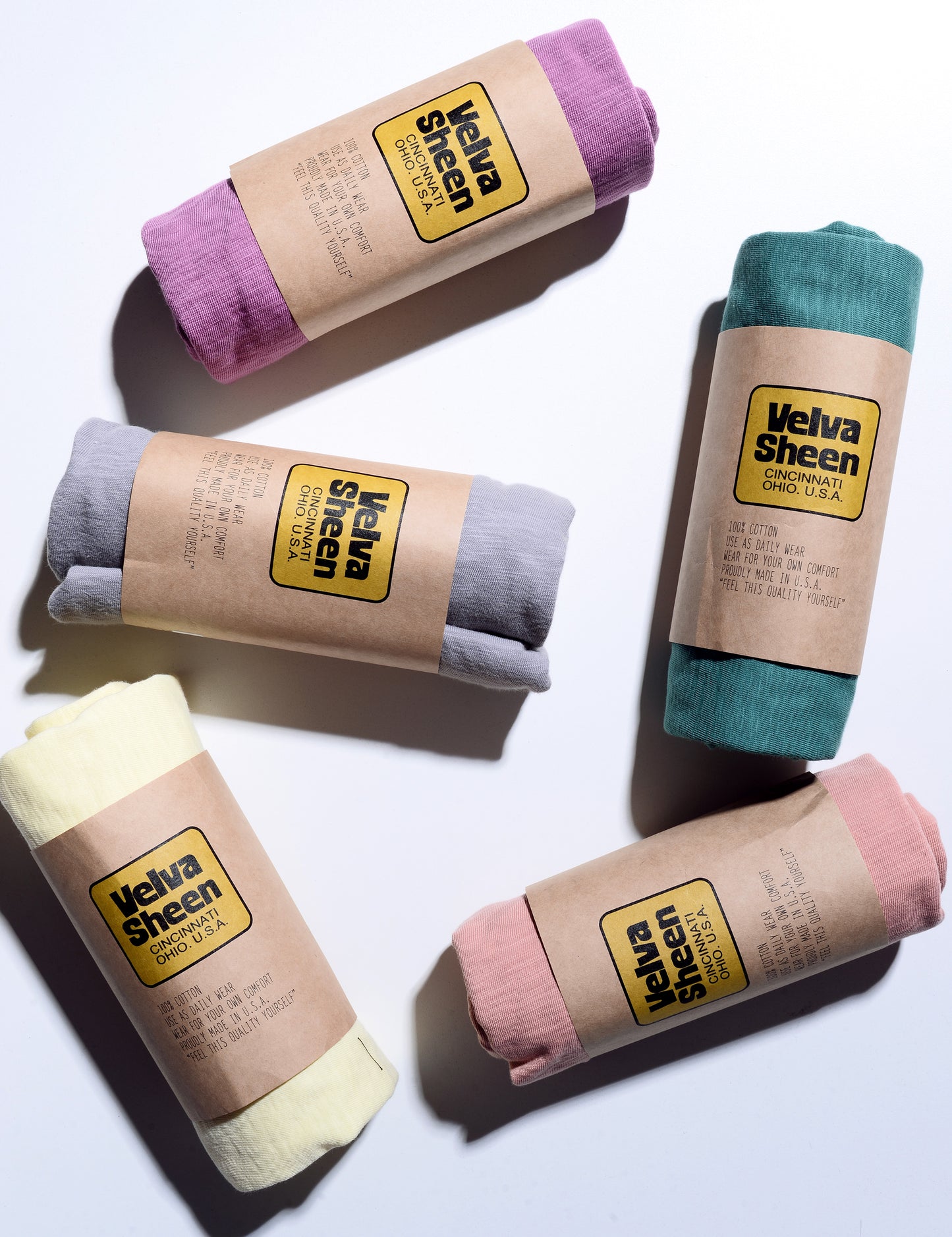 Photo of several colors of Velva Sheen Crewneck T-Shirts rolled in their paper packaging