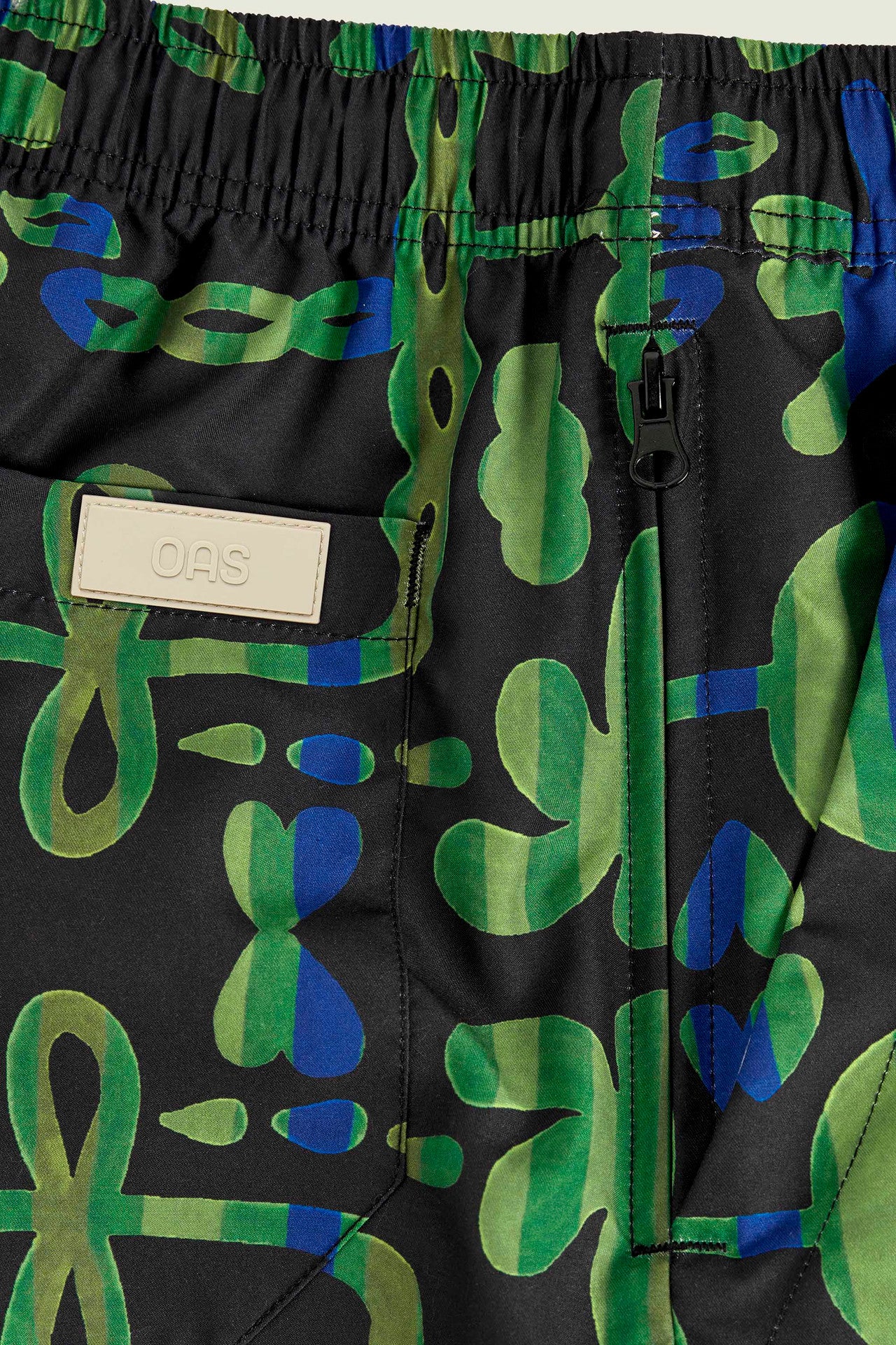 Detail of OAS Feral Galbanum Swim Shorts showing side pocket and label