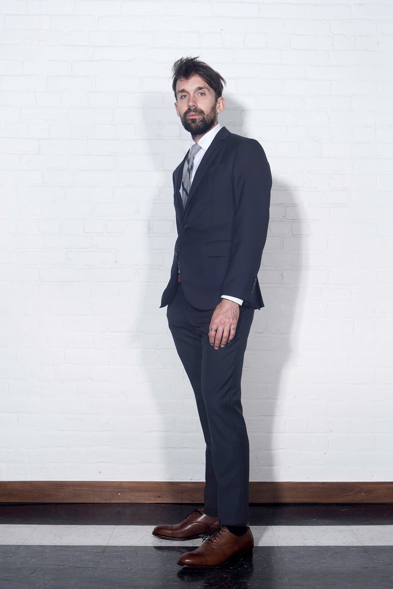 brooklyn Tailors BKT50 Tailored Trouser in Super 110s Plainweave - Classic Navy on-body shot. Model is wearing the trousers with matching jacket, white dress shirt, tie, and brown dress shoes. 