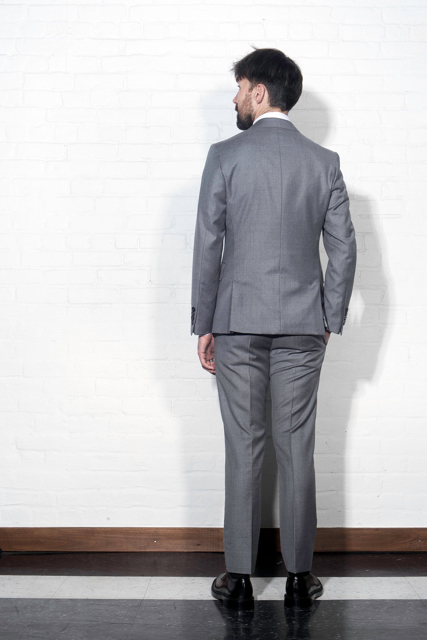 Brooklyn Tailors BKT50 Tailored Jacket in Super 110s Twill - Dove Gray on-body shot from the back. Model is wearing jacket with matching pants, white dress shirt, tie, and black belt.