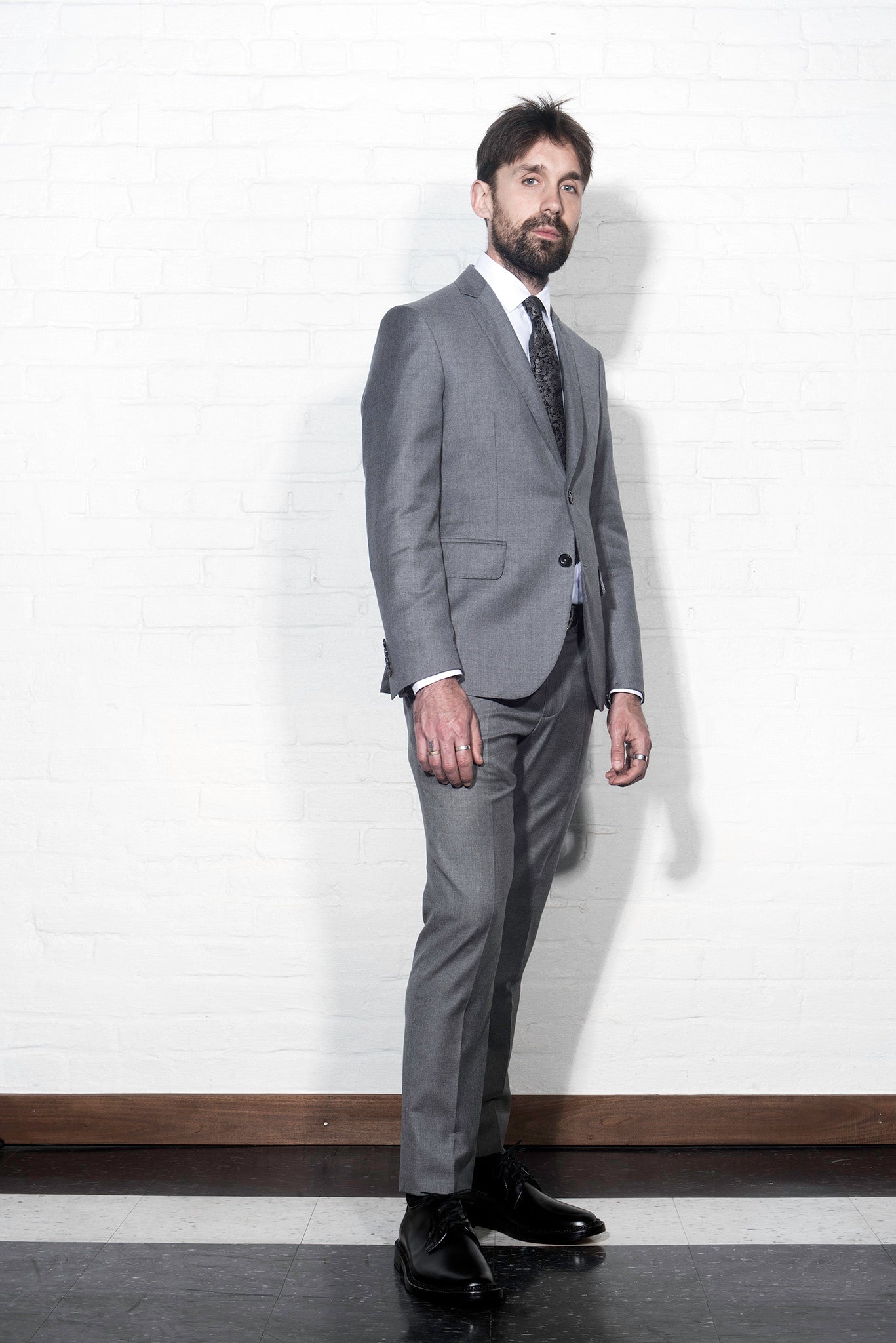 Brooklyn Tailors BKT50 Tailored Jacket in Super 110s Twill - Dove Gray on-body from the side shot. Model is wearing jacket with matching pants, white dress shirt, tie, and black belt.