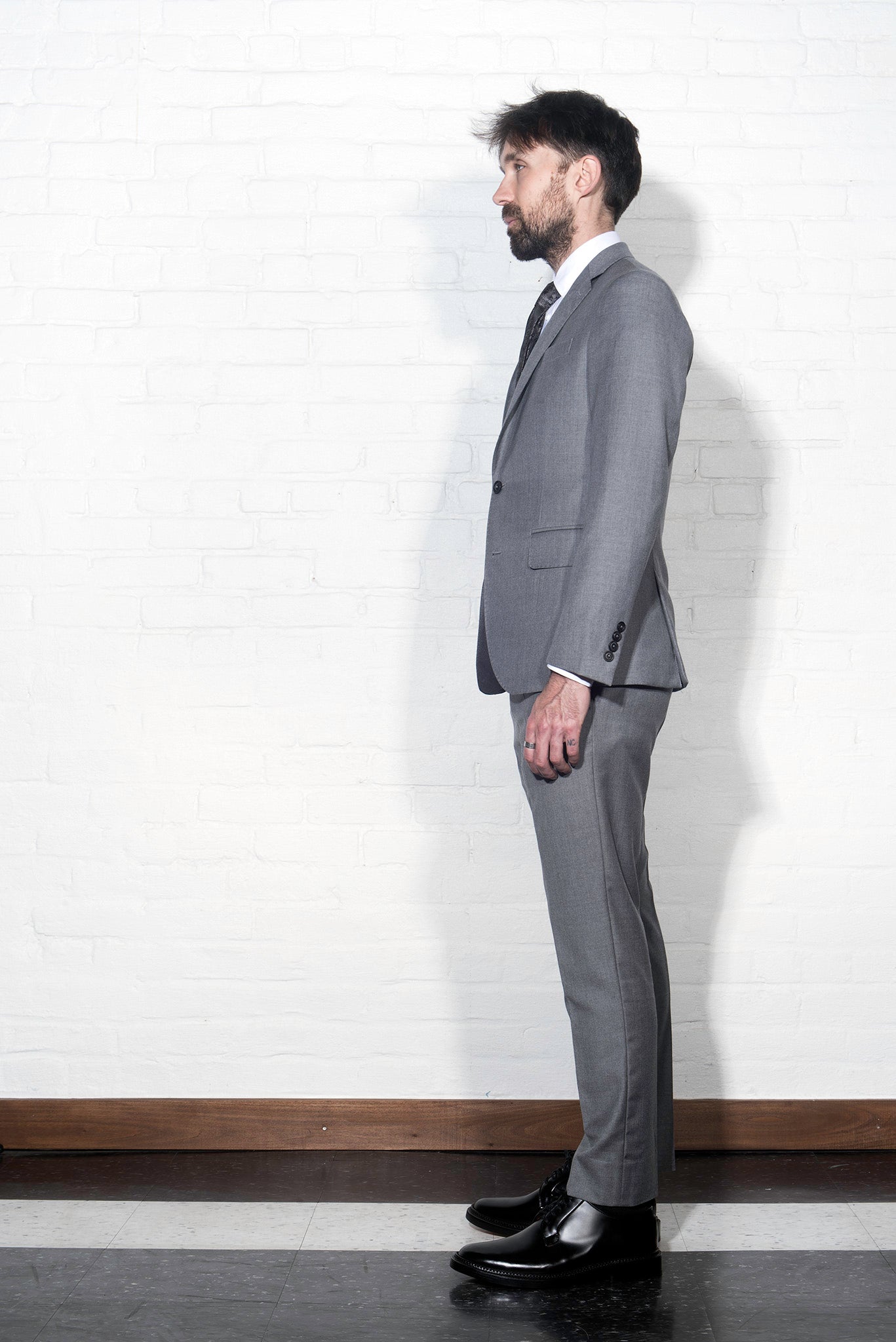 Brooklyn Tailors BKT50 Tailored Trouser in Super 110s Twill - Dove Gray on-body shot. Model is wearing pant with matching jacket, white dress shirt, and tie. Photo taken from side.