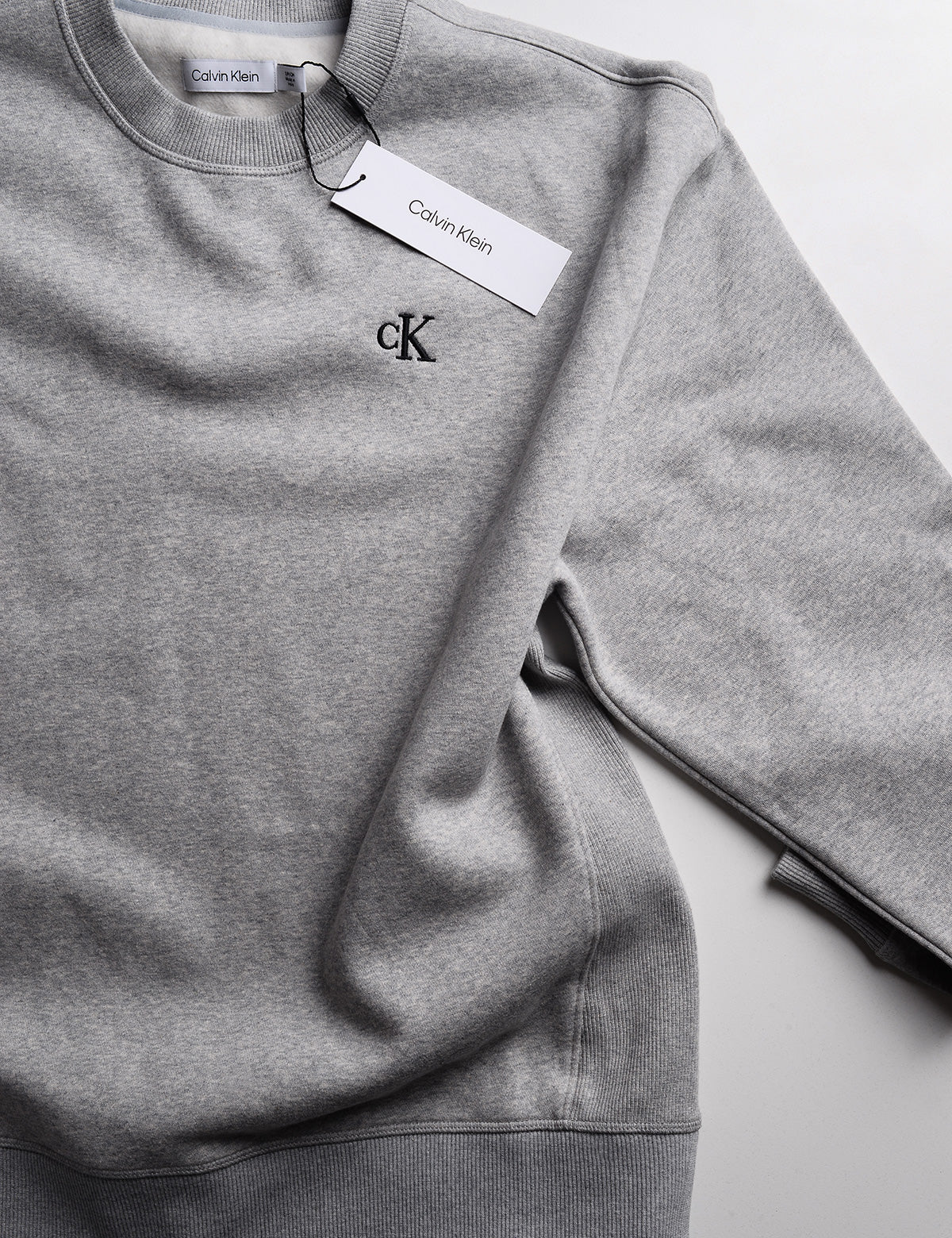 Detail of Calvin Klein Archive Logo Fleece Crewneck - Heroic Heather Gray showing logo, neck, and tag