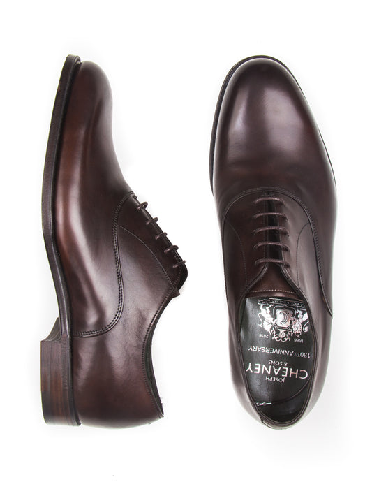 Flat shot of Joseph Cheaney Welland Oxford Shoes in Mocha Calf Leather. One shoe is on its side to show profile