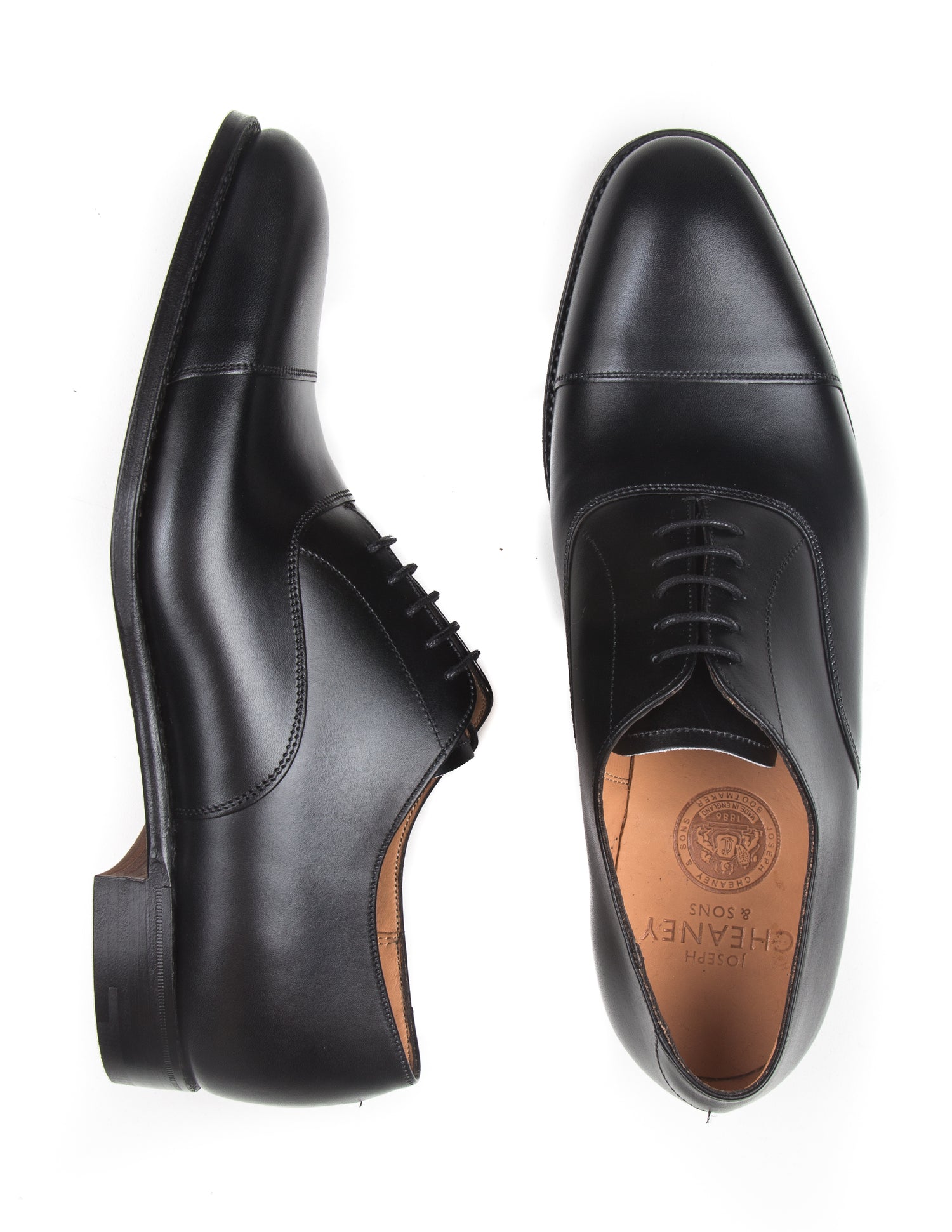 Flat shot of Joseph Cheaney Lime Oxford Shoes in Black Calf Leather. One shoe is on its side to show profile