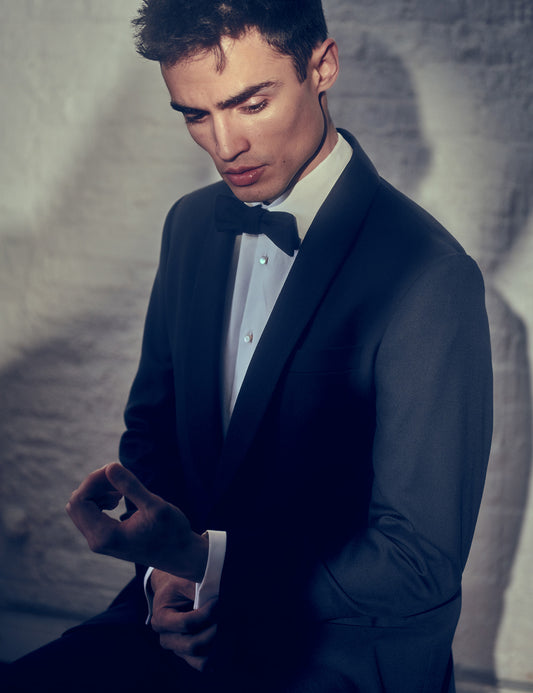 On-body shot of Brooklyn Tailors BKT50 Tuxedo Trouser in Super 120s Twill - Black with Grosgrain Stripe. Model is wearing trouser with matching tuxedo jacket, white tuxedo shirt, shirt studs, and black bowtie