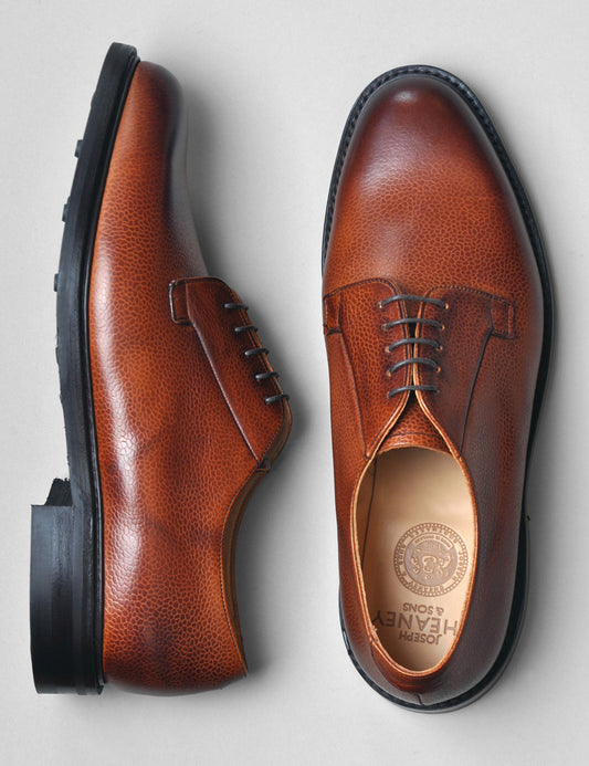 Flat shot of Joseph Cheaney Deal II Derby in Mahogany Grain Leather. One shoe is on its side to show the profile