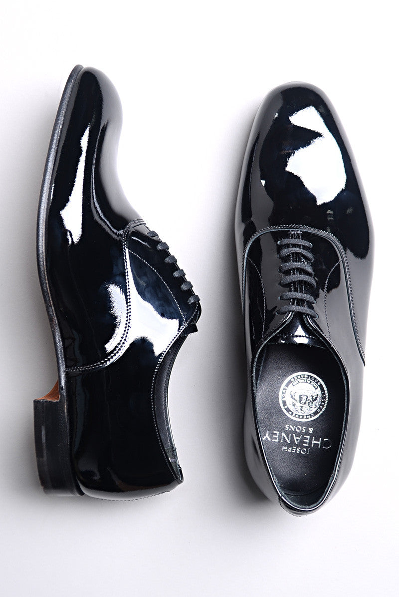 Flat shot of Joseph Cheaney Kelly in Black Patent Leather Oxford. One shoe is on its side to show profile
