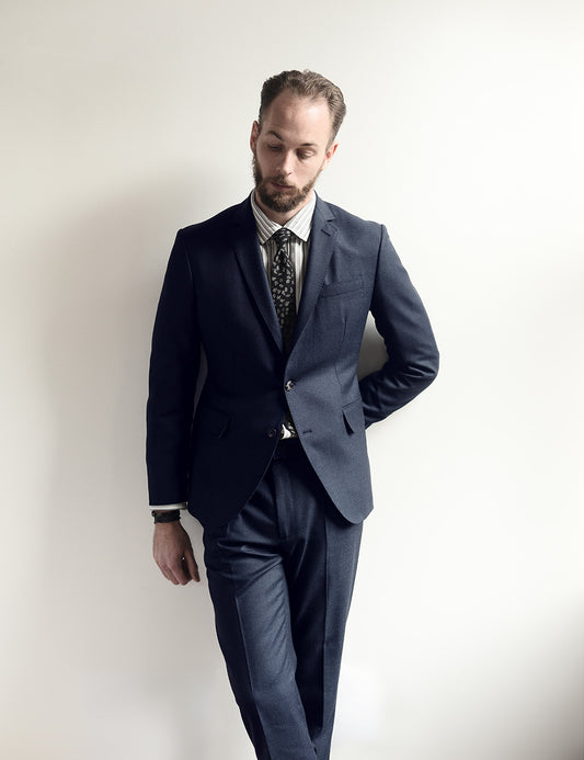 Model wears navy suit, white dress shirt, and silk tie. 