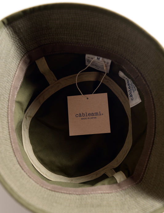 Interior shot of Cableami Organic Cotton Herringbone Bucket Hat - Olive showing labels, taping, and tag