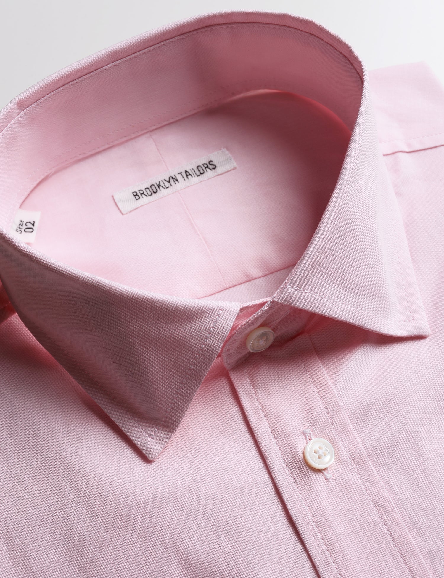 Detail shot of collar, labeling, buttons, and fabric texture on Brooklyn Tailors BKT20 Slim Dress Shirt in Pinpoint Oxford - Rose Quartz