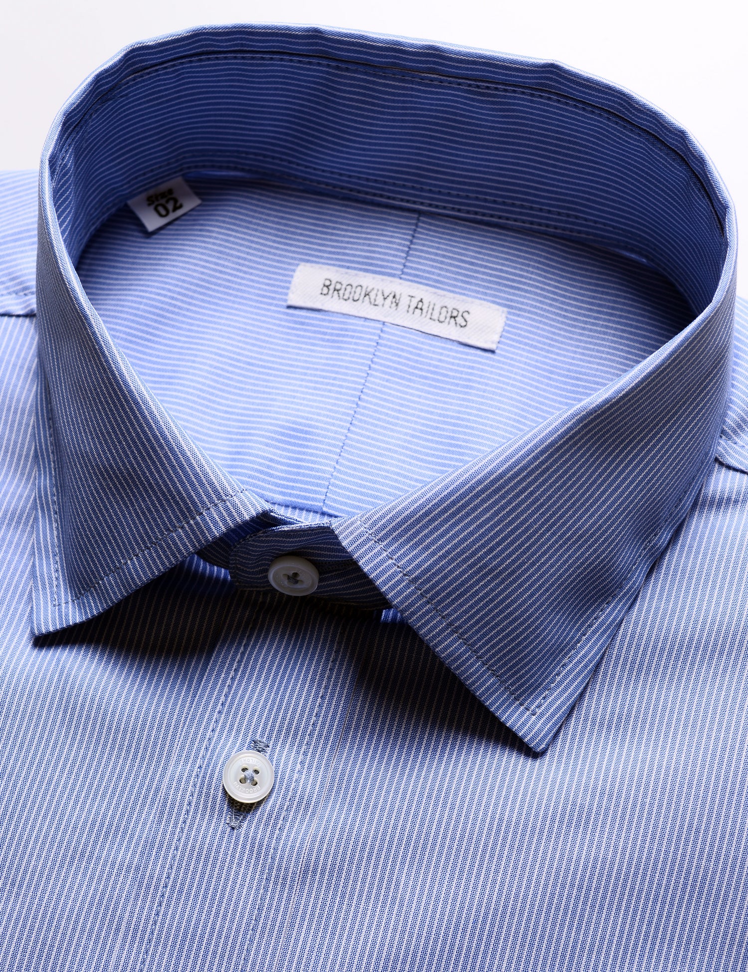 Detail shot of collar, buttons, labeling, and fabric pattern on Brooklyn Tailors BKT20 Slim Dress Shirt in Professional Stripe - Imperial Blue