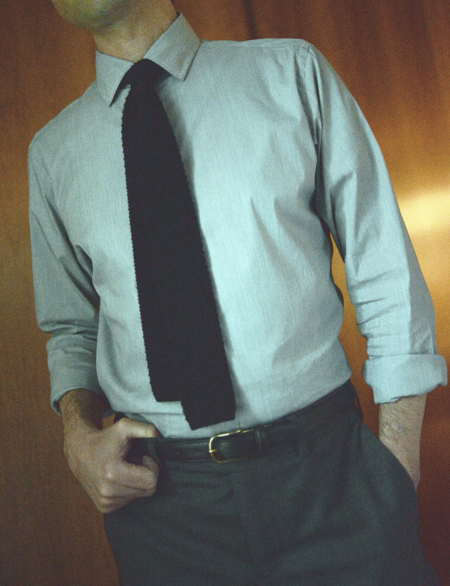 Photo of Brooklyn Tailors x Saddler's 25mm Belt in Grain Leather - Black on body. The model is wearing a dress shirt, suit trousers, and a knit tie. 