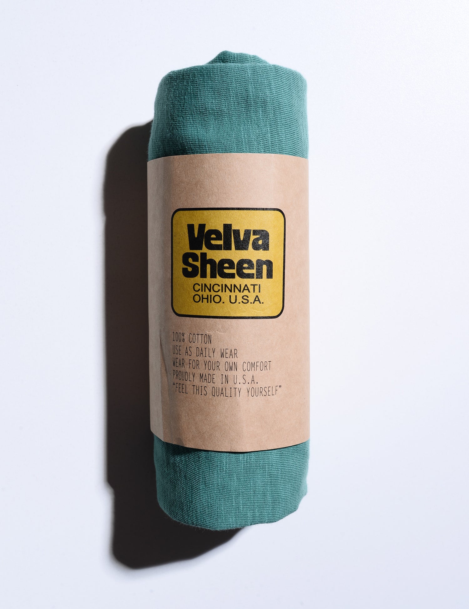 Photo of Velva Sheen Crewneck T-Shirt in Foggy Green rolled in its paper packaging
