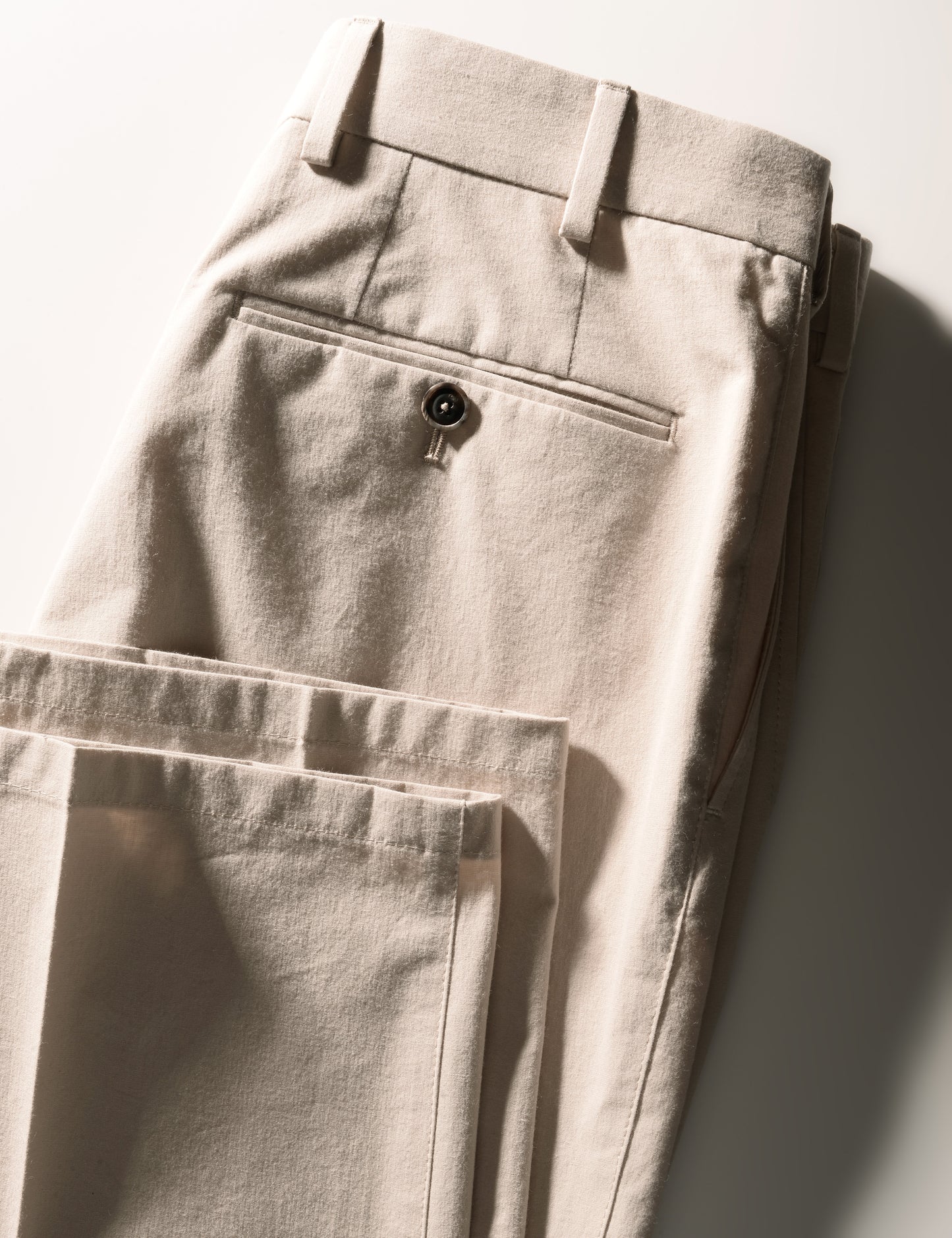 Detail showing back of folded Brooklyn Tailors BKT36 Straight Leg Pant in Crisp Cotton Blend - Desert Sand showing back pocket, hem, and waistband