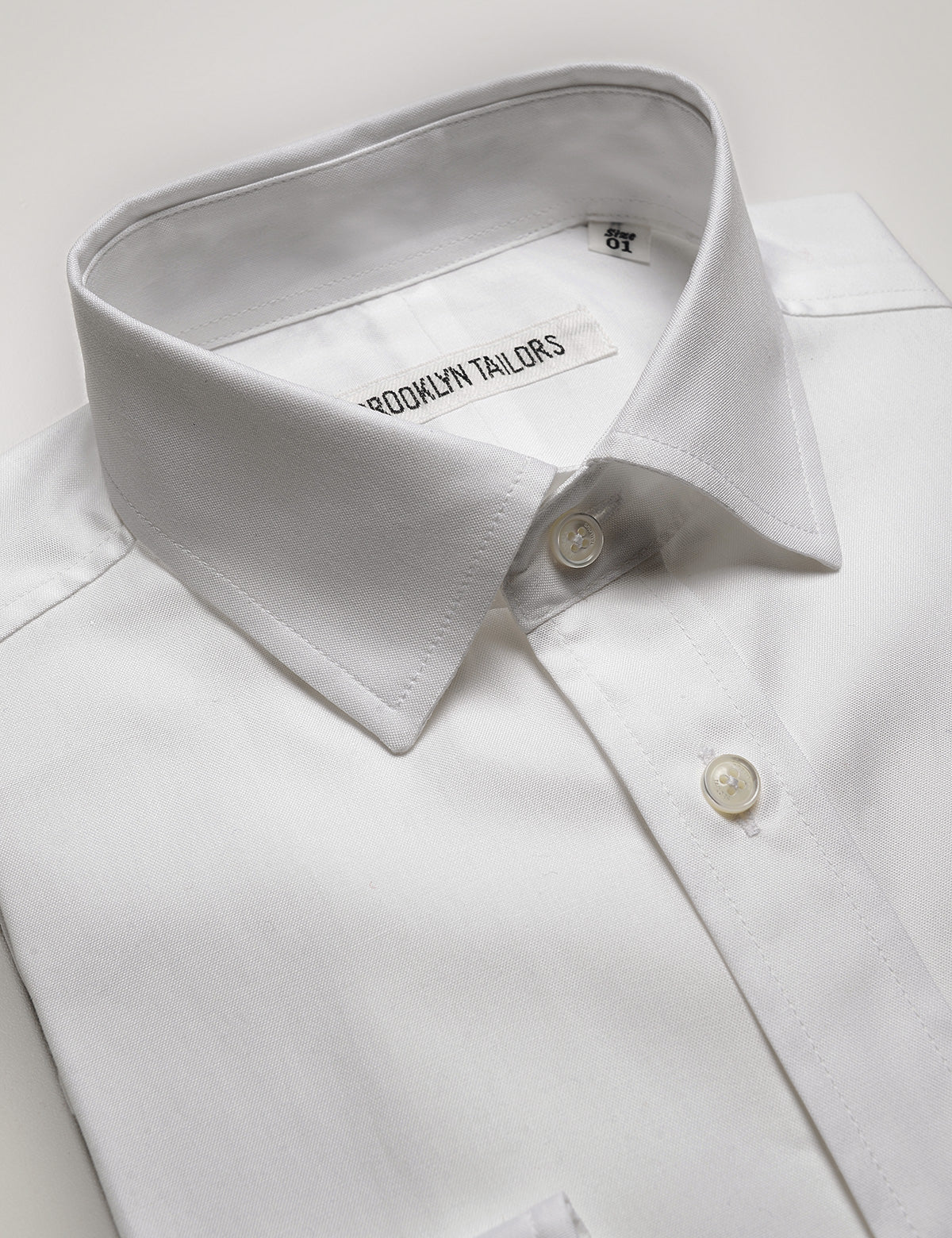 Detail of collar, buttons, labeling, and fabric texture on Brooklyn Tailors BKT20 Slim Dress Shirt in Pinpoint Oxford - White