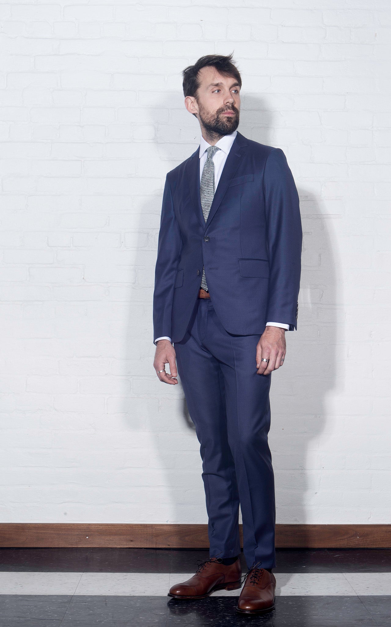On-body shot of Brooklyn Tailors 2020 Version BKT50 Tailored Jacket in Super 120s Twill - Bright Navy. Model is wearing jacket with matching pants, white dress shirt, and tie. Photo taken from side