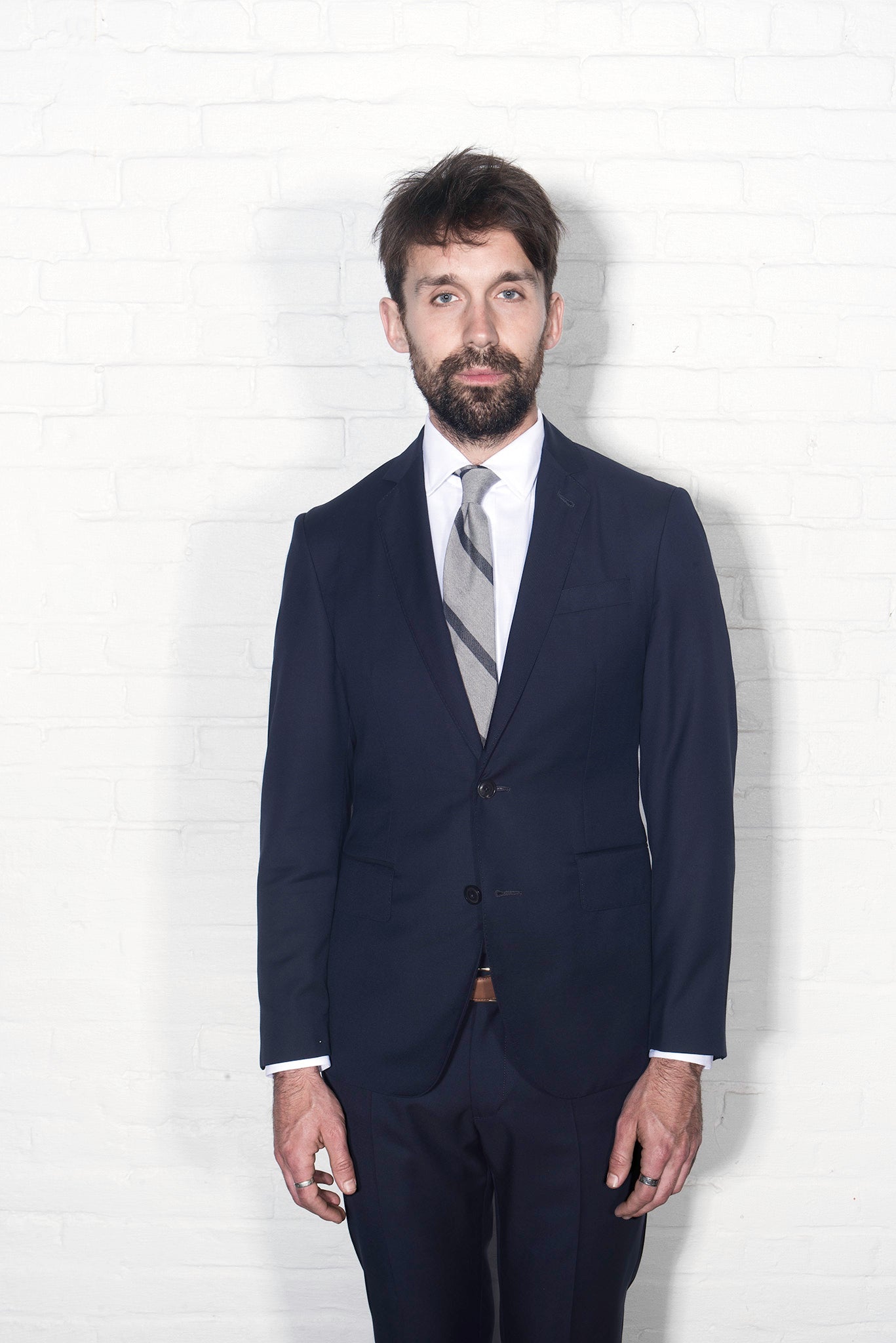 Brooklyn tailors BKT50 Tailored Jacket in Super 110s Plainweave - Classic Navy on-body shot. Model is wearing the jacket with matching pants, a white dress shirt and gray striped tie. 