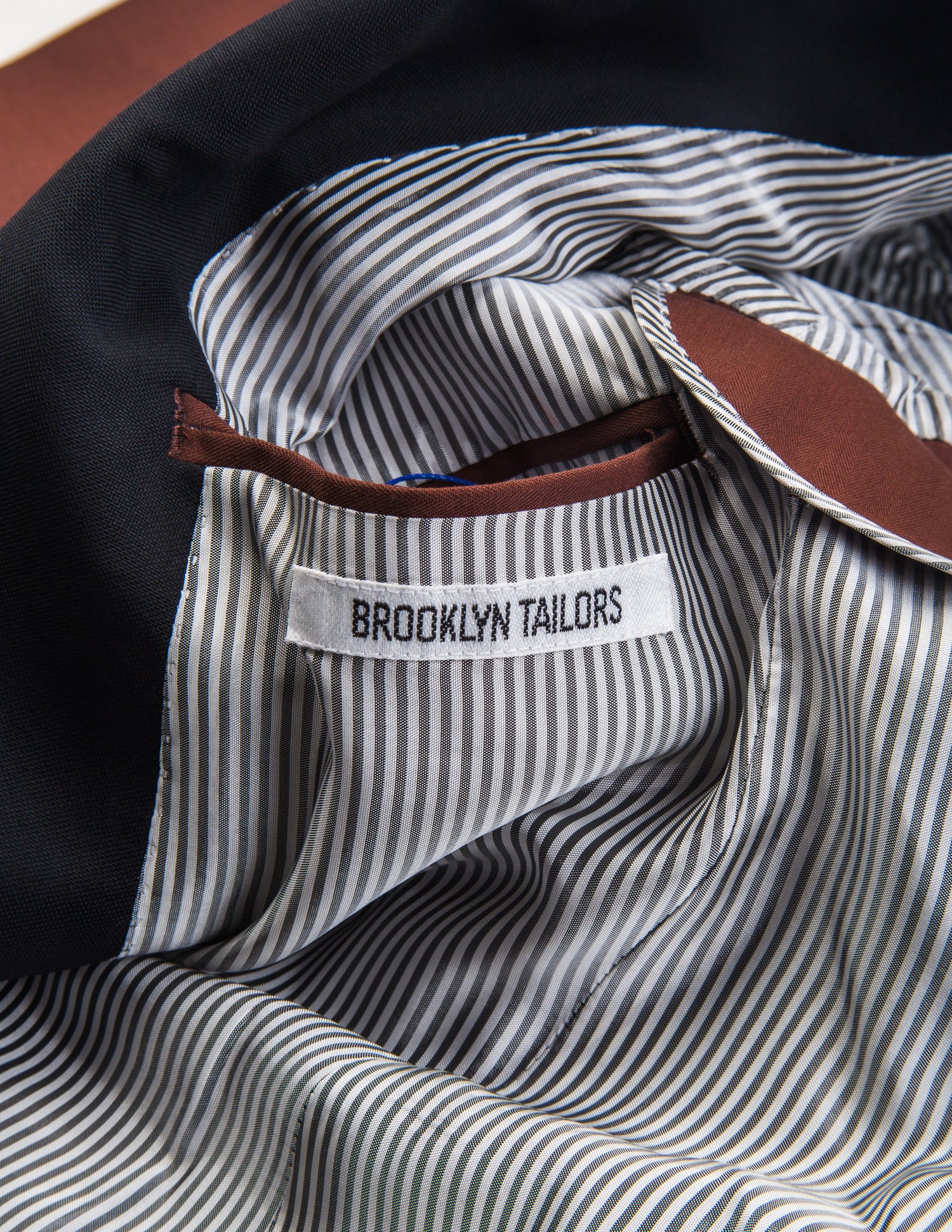 Detail shot of Brooklyn Tailors BKT50 Shawl Collar Dinner Jacket in Herringbone Wool/Cotton - Brick showing lining and Brooklyn Tailors label on the interior of the jacket