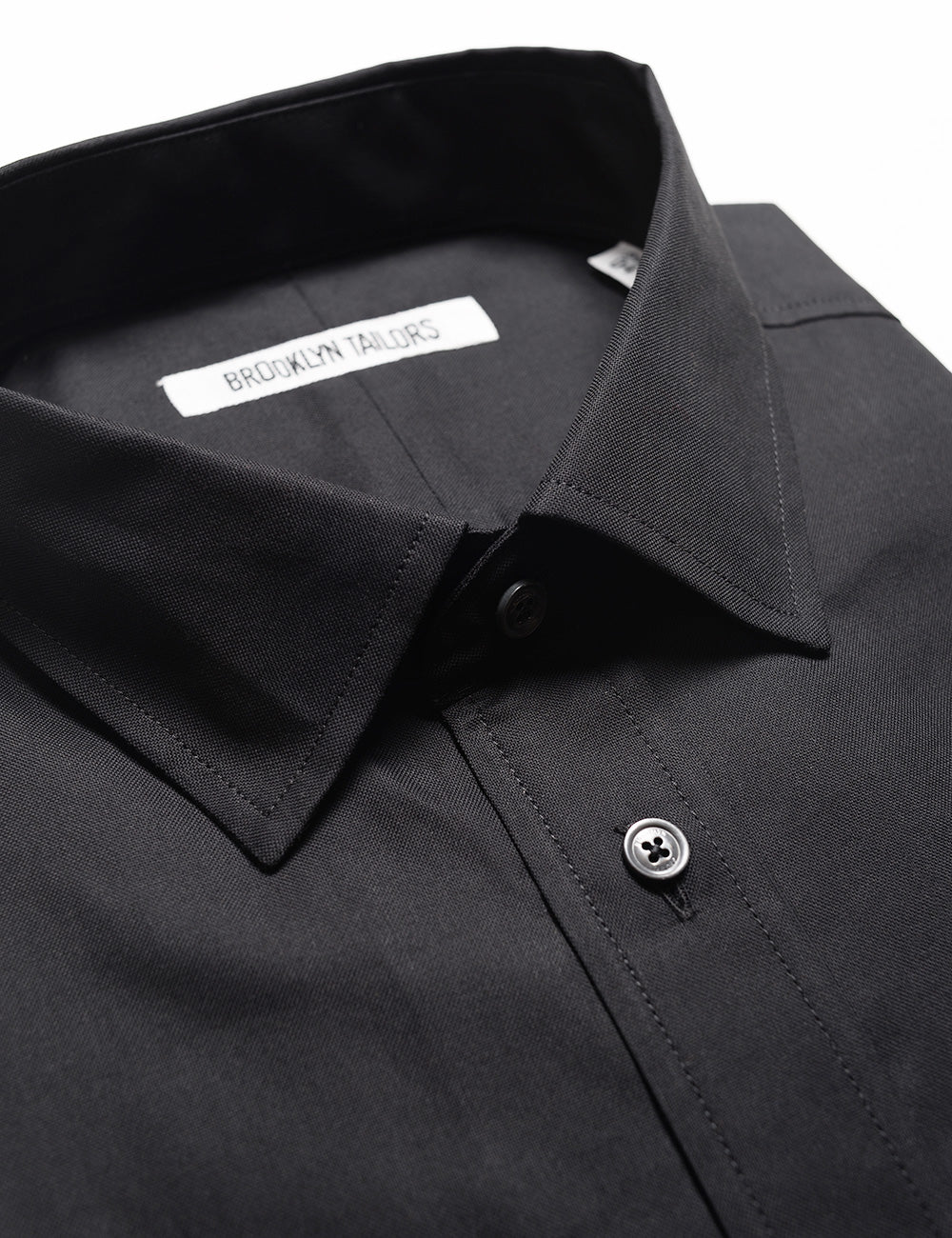 Detail shot of collar, labels, buttons, and fabric texture on Brooklyn Tailors BKT20 Slim Dress Shirt in Pinpoint Oxford - Black