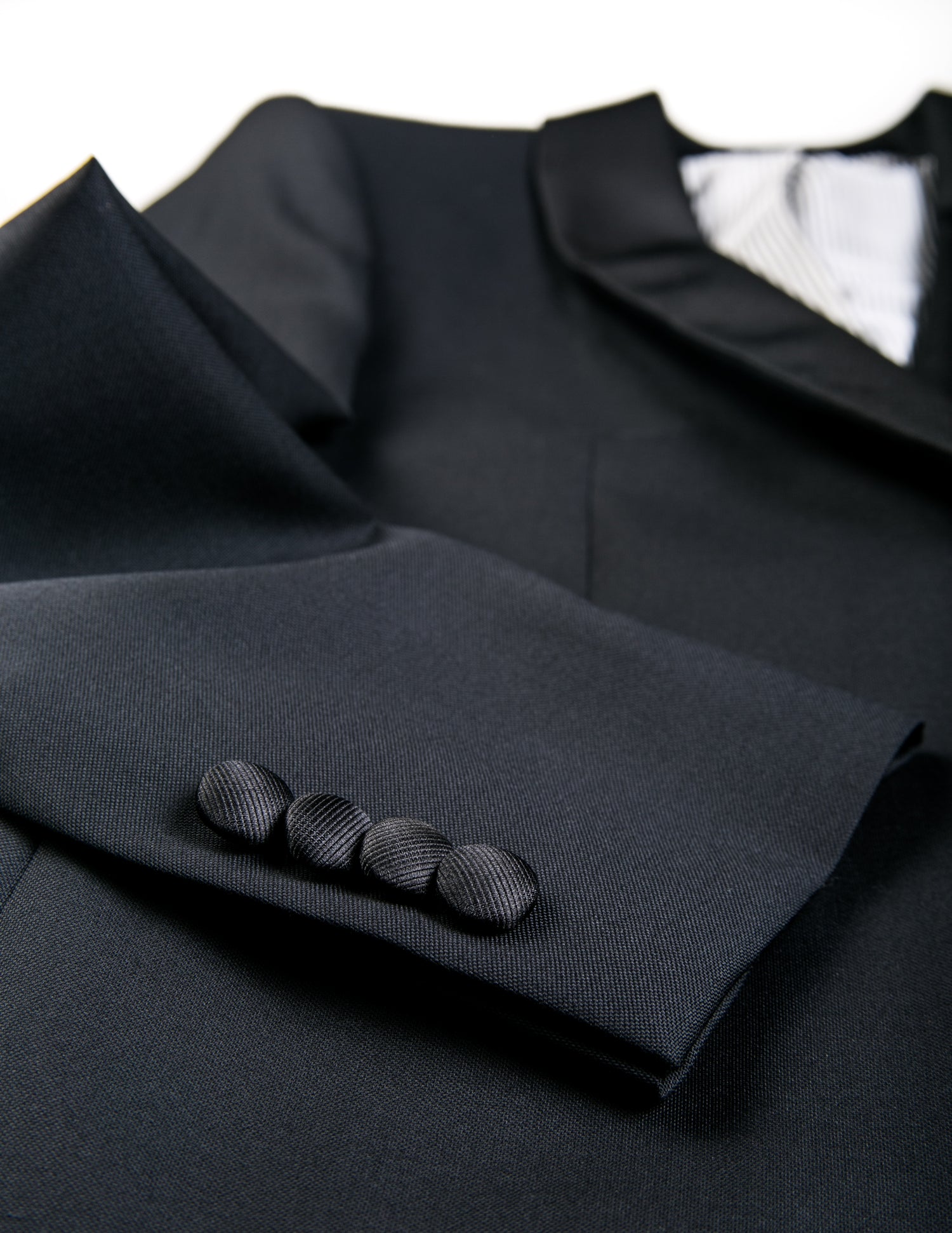 Detail shot of Brooklyn Tailors BKT50 Shawl Collar Tuxedo Jacket in Super 110s - Black with Grosgrain Lapel showing sleeve, covered buttons, and fabric texture