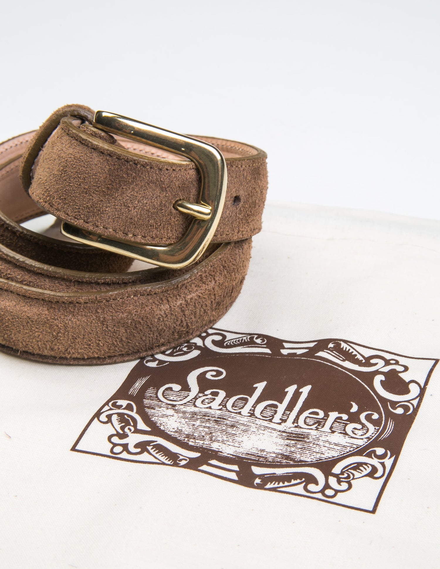 Photo of Brooklyn Tailors x Saddler's 25mm Belt in Suede Leather - Clay coiled next to the fabric bag it is sold with. 