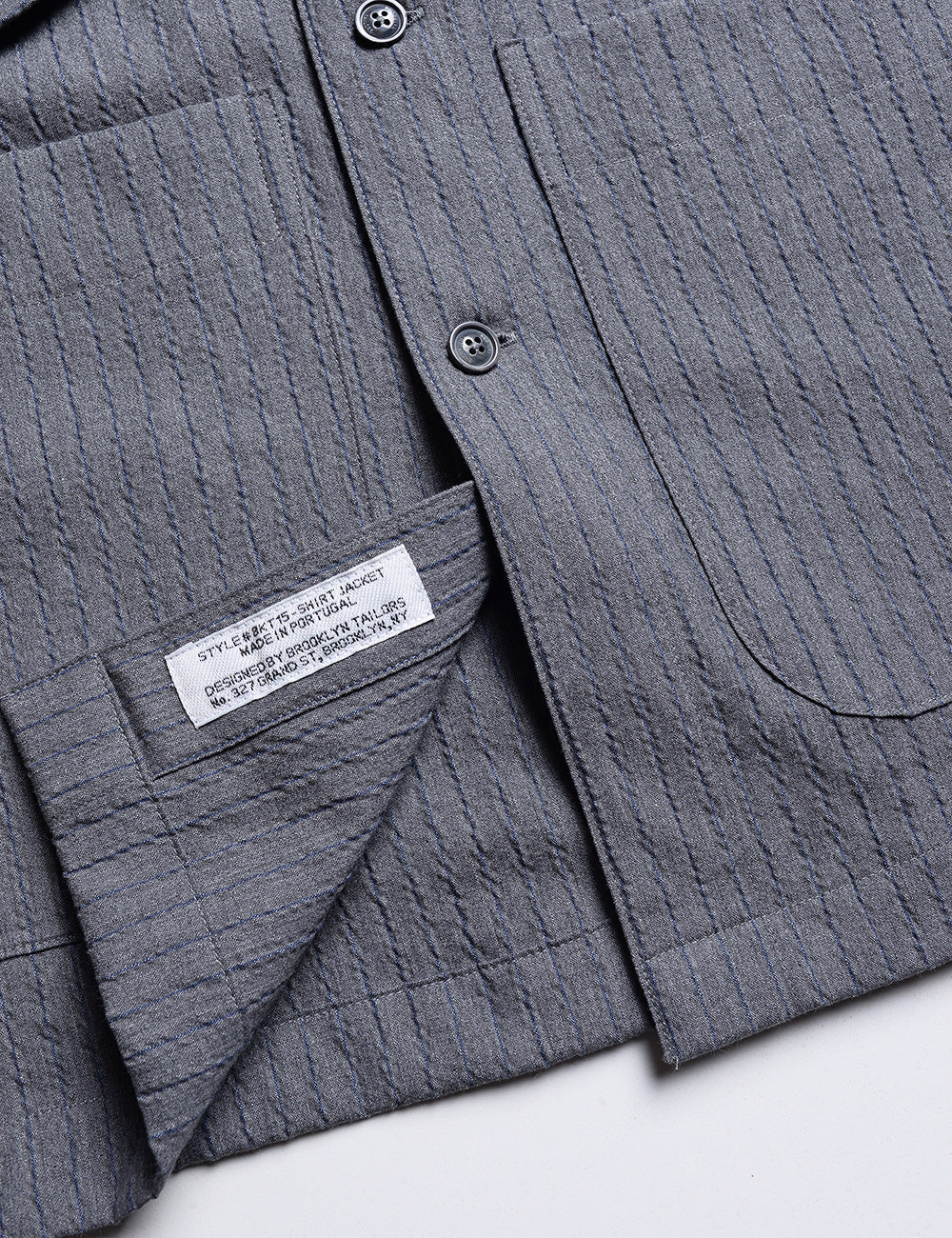 Detail of BKT15 Shirt Jacket in Cotton Seersucker - Thunder Stripe showing hem and interior labeling