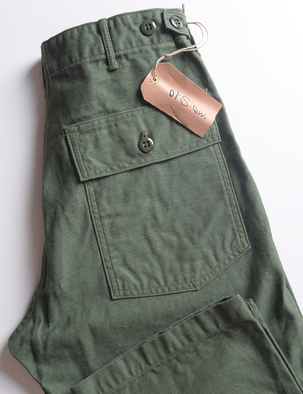 Folded detail of Orslow US Army Fatigue Trousers - Army Green showing back pocket and tag