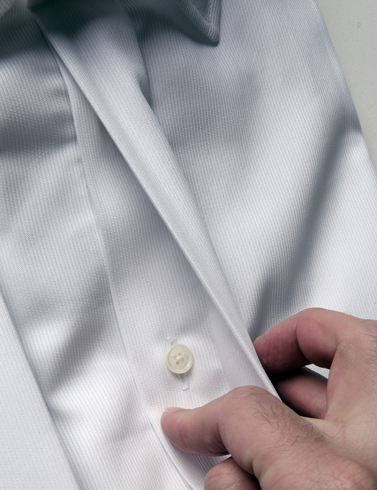 Detail showing hand moving covering to reveal buttons underneath on French Cuff Tuxedo Shirt With Covered Buttons - Bar Pique