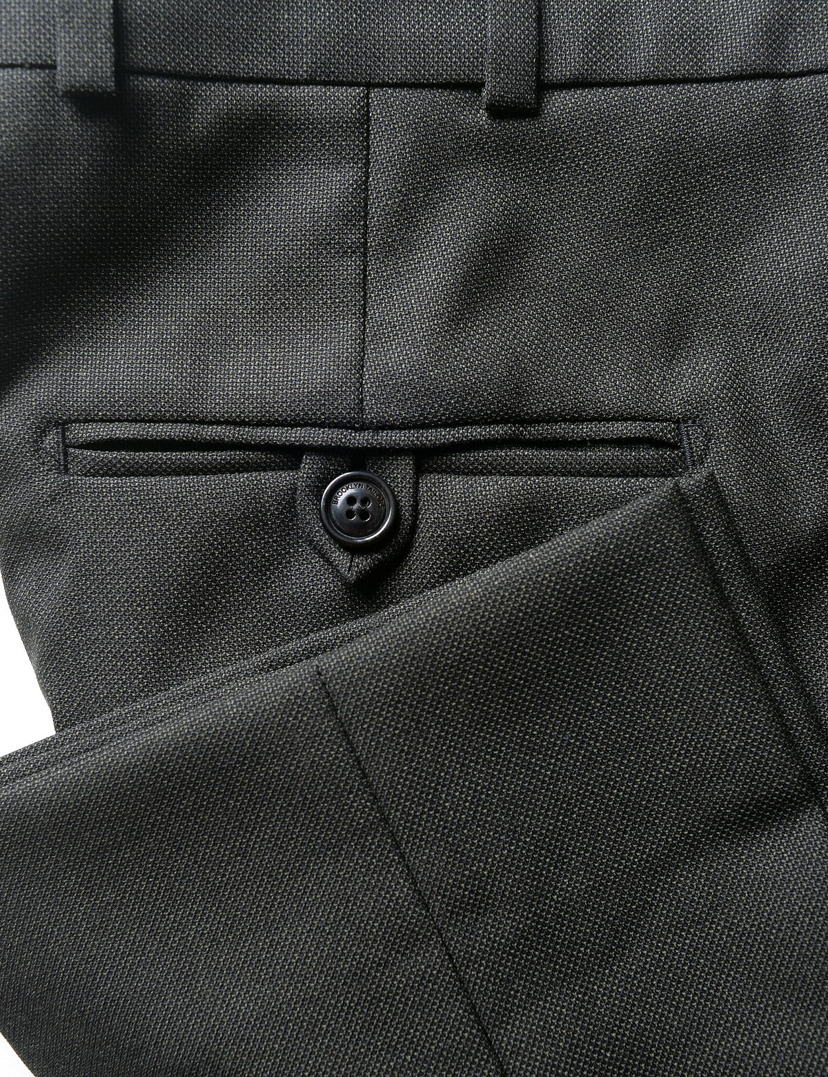 Detail shot of BKT50 Tailored Trousers in Textured Wool - Wrought Iron showing back pocket, hem, and fabric texture