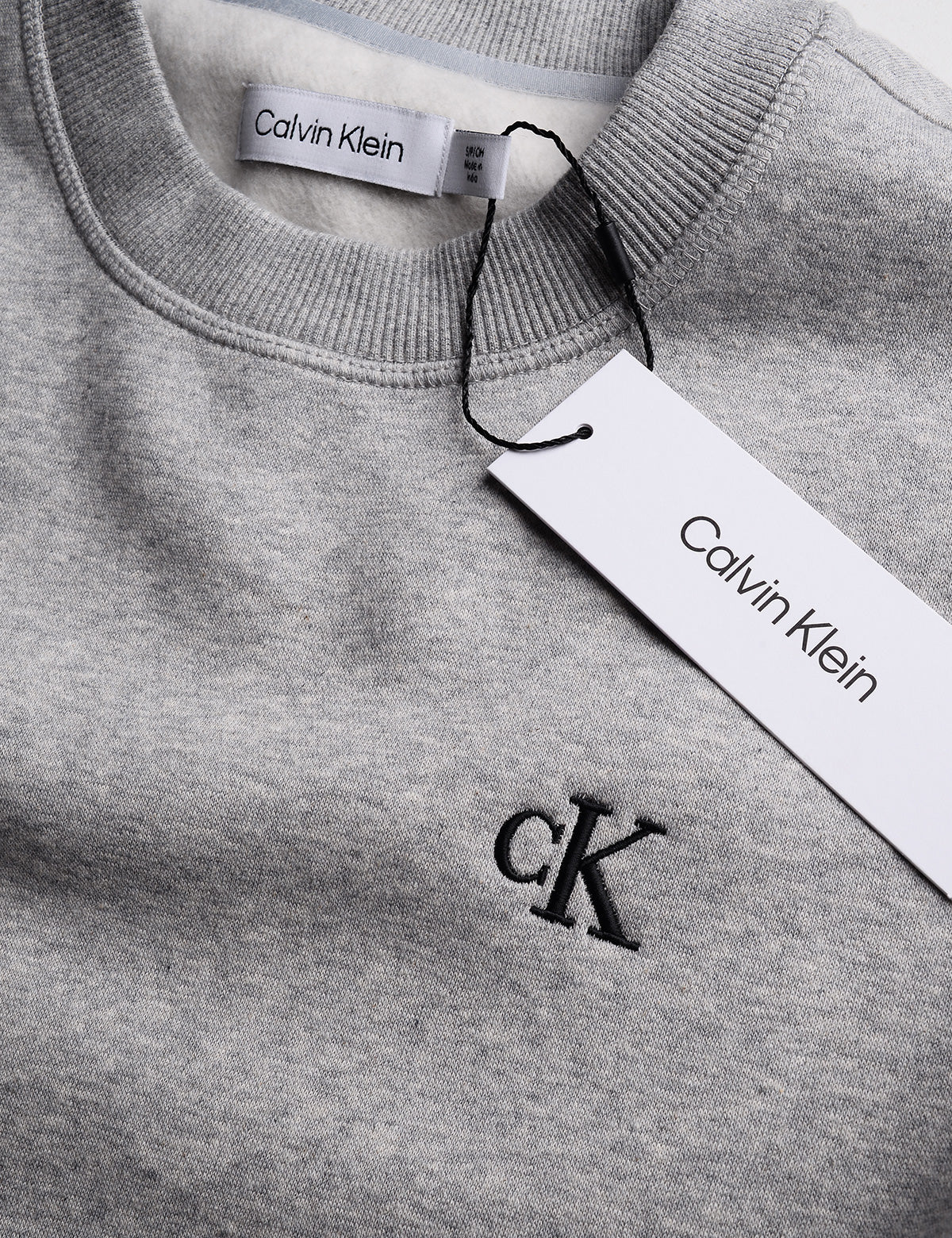 Detail of Calvin Klein Archive Logo Fleece Crewneck - Heroic Heather Gray showing logo, neck, and tag
