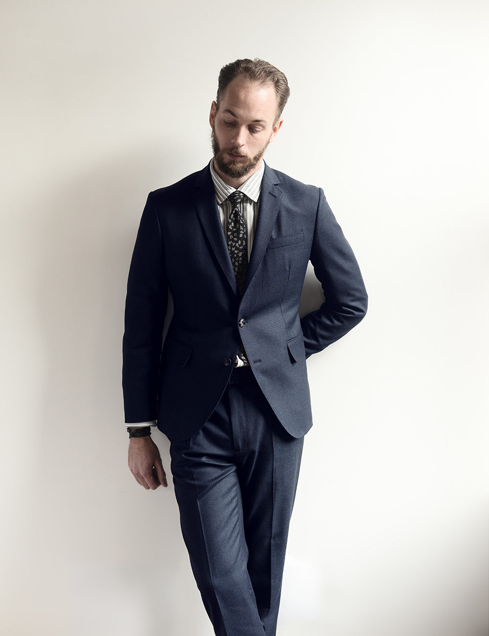 On-body shot of BKT50 Tailored Jacket in Birdseye Weave - Navy. Model is wearing jacket with matching pants, striped dress shirt, and tie.