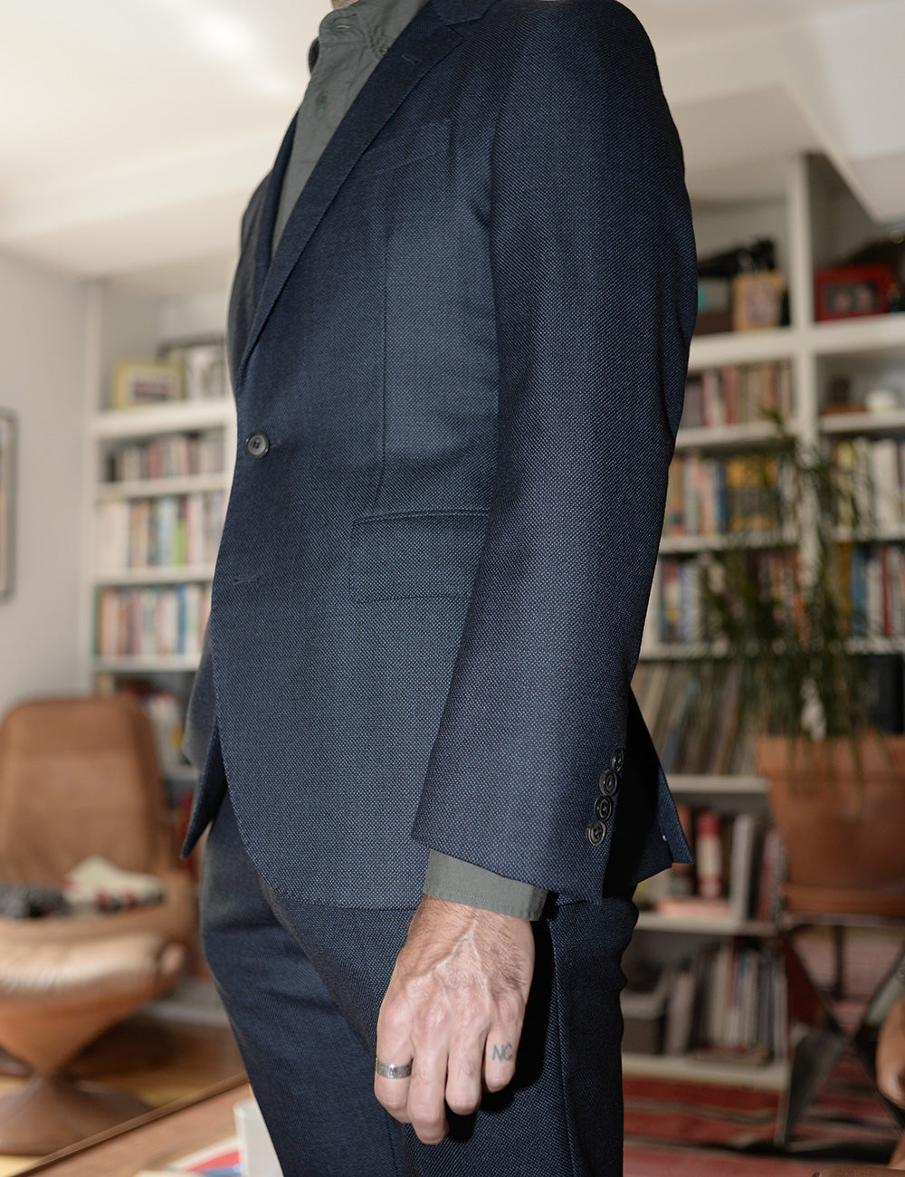 On-body shot of BKT50 Tailored Jacket in Birdseye Weave - Navy. Model is wearing jacket with matching pants and green button down shirt. Photo taken from side