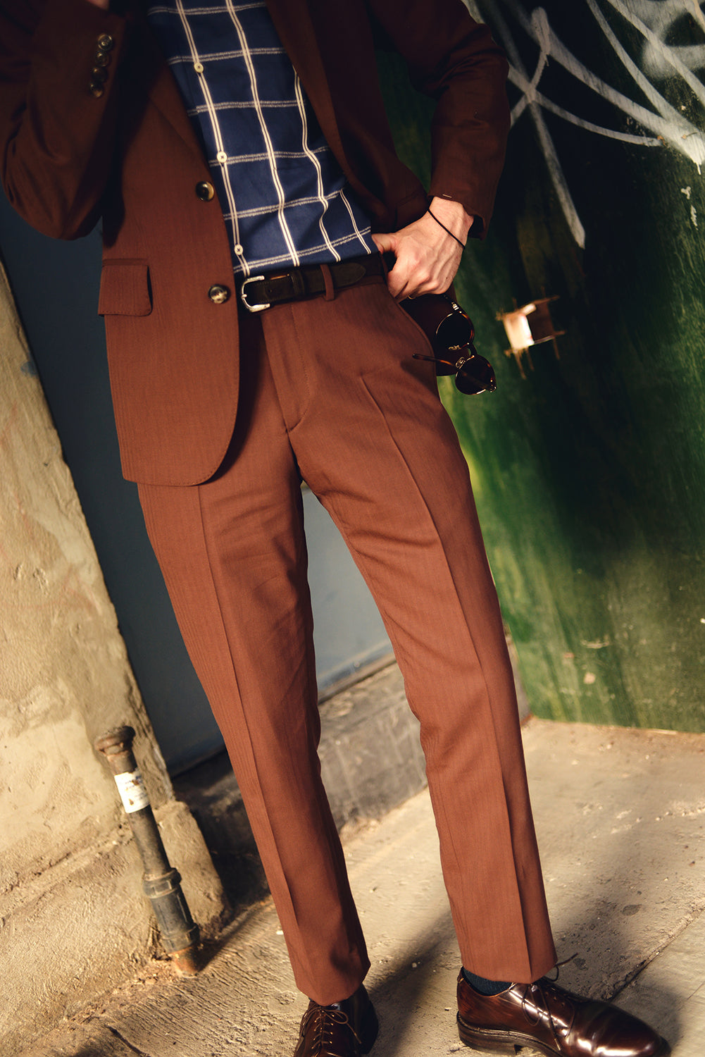Brooklyn Tailors BKT18 Camp Shirt in Blue Windowpane on-body shot. Model is wearing a rust color suit, brown dress shoes, and brown belt with the shirt. He is holding sun glasses. 